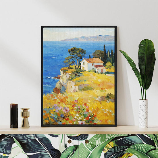 black frame wall art painting depicting a cliffside cottage by the sea