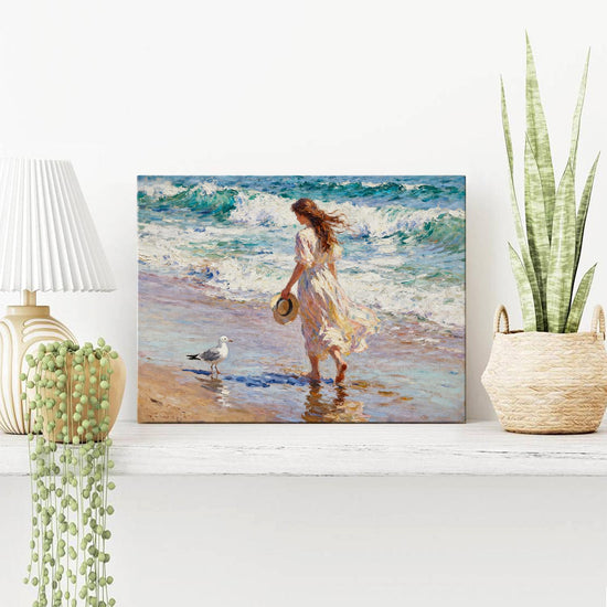 wall art painting on the table depicts a woman in a flowing long dress walking on the beach, accompanied by seagulls.