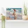 wall art painting on the table depicts a woman in a flowing long dress walking on the beach, accompanied by seagulls.